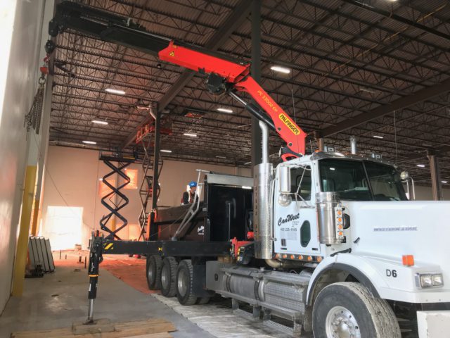 Crane & Picker Services. Boom truck being used to remove a concrete wall panel in a wearhouse. 